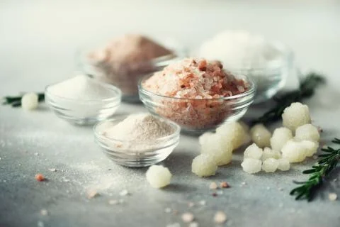 Mix of different salt types on grey concrete background. Sea salts, black and Stock Photos