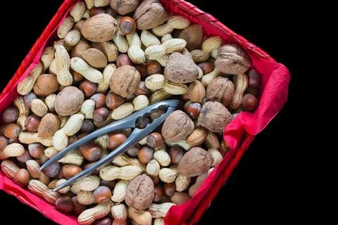 Mix of dried fruit with shell in a red basket with a nutcracker Stock Photos