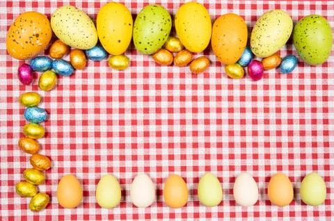 Mix of easter eggs of all colors and sizes on a background of red and white g Stock Photos