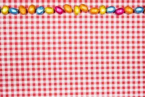 Mix of easter eggs of all colors and sizes on a background of red and white g Stock Photos