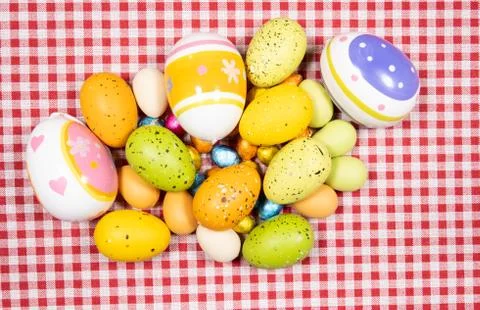 Mix of easter eggs of all colors and sizes on a background of red and white g Stock Photos