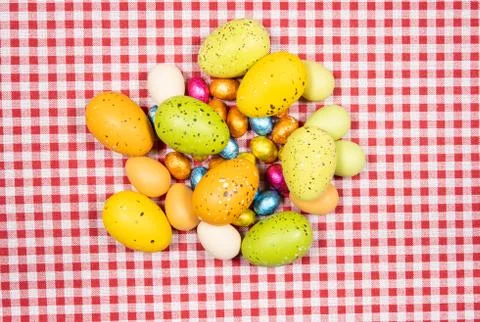Mix of easter eggs of all colors and sizes on a background of red and white g Stock Photos