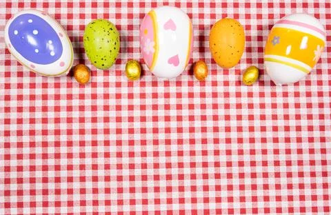 Mix of easter eggs of all colors and sizes on a background of red and white g 写真素材