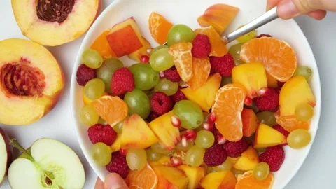Mix fruit salad with a spoon, assorted nectarines, grapes, apples, raspberries Stock Footage 252081542