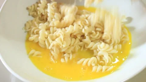 Mix macaroni with beaten eggs. Mix macaroni and eggs in a bowl Stock Footage 334647395