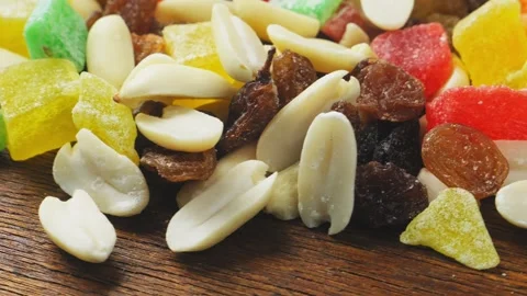 Mix of multi-colored dried fruits, candied fruits and scattered nuts on a w.. 库存影片 271152603