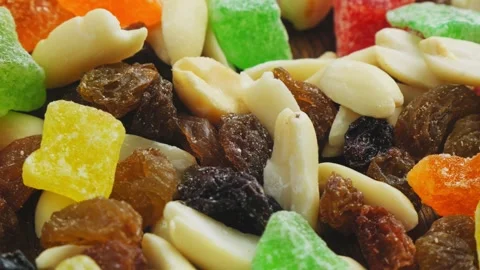 Mix of multi-colored dried fruits and nuts scattered on a wooden surface Stock Footage 274019724