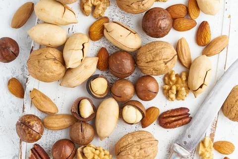 Mix of nuts - walnut, almonds, pecans, macadamia and knife for opening shell Stock Photos