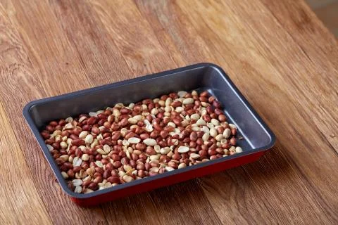 Mix of peeled raw peanut on baking tray over wooden background, selective focus Stock Photos