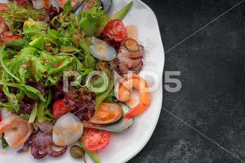 Photograph: Mix salad with seafood on a dark background #201130662