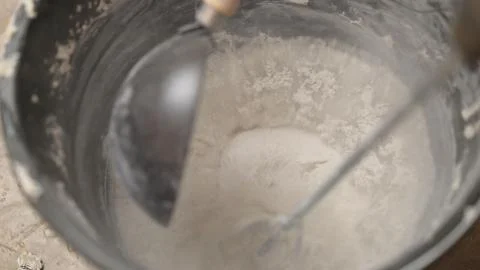 Mix the solution in a bucket using a construction mixer. Worker mixing plaste Stock Photos