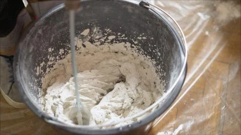 Mix the solution in a bucket using a construction mixer. Worker mixing plaste Stock Photos