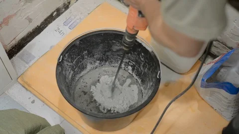 Mix the tile adhesive with an electric hand mixer Stock Footage 77009646