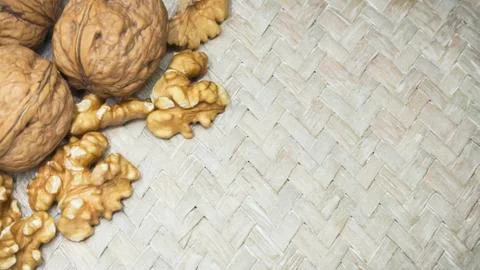 Mix of walnuts shells and walnut kernels on light wicker surface, with space for Foto stock