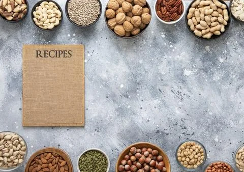 Mixed assorted nuts and seeds in various bowls on light kitchen table Stock Photos