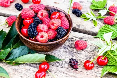 Mixed berries of raspberry, cherry, mulberry in a bowl on wooden background. Stock Photos