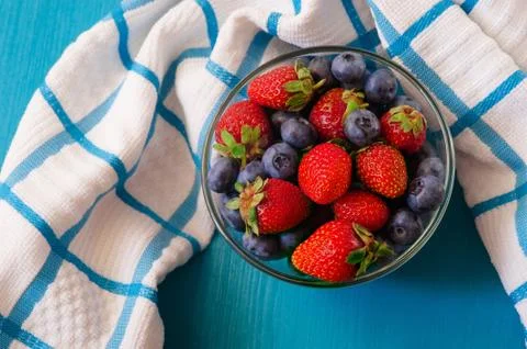 Mixed berries in a a transparent cup on brown wooden background Stock Photos