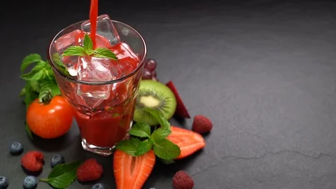 Mixed berry and beetroot pouring into tall glass with surrounding fruits . Stock Footage 129582032