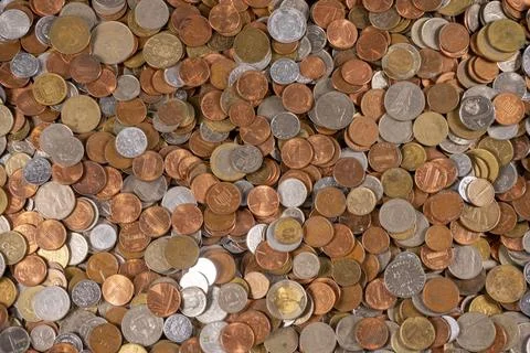 Mixed coins spread out on a flat surface in a casual arrangement Stock Photos