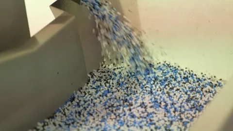 Mixed-color pellets falling into trough in industrial manufacturing plant Video stock 342604219