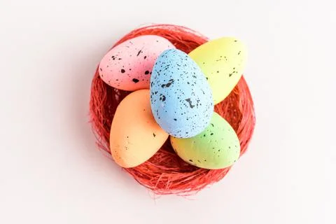 Mixed colored decorative red Easter eggs in a red rustic basket isolated Stock Photos