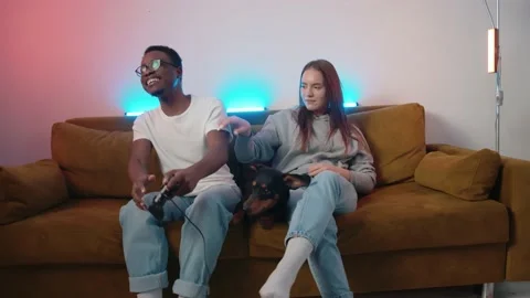 A mixed couple with a dog are resting at home and a young girl laughingly fights Stock Footage 173418005