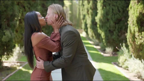 A mixed couple joyfully proposing in a park under a beautiful sky, celebrating Vídeo Stock 286248434