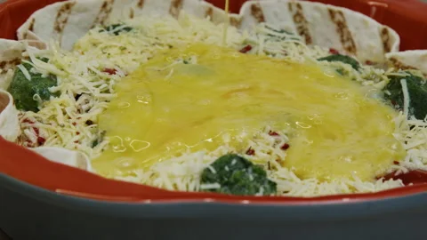 Mixed eggs are being poured and distributed on cheese, tomatoes and spinach. Stock Footage 266423254