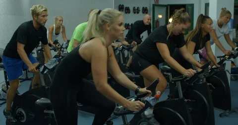 A mixed exercise bike class peddling hard in the gym. Vídeos de archivo 85535843