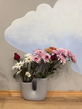 Mixed flowers in a U-shaped ceramic vase are placed on the floor Foto stock