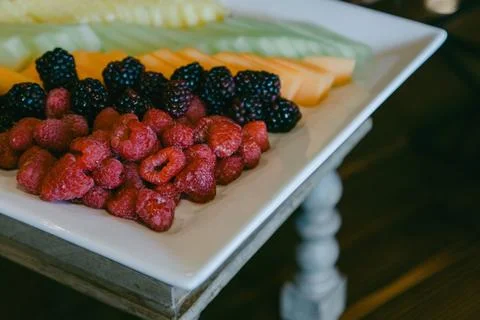 Mixed fruit platter featuring fresh berries and melons served on a white plate Stock Photos