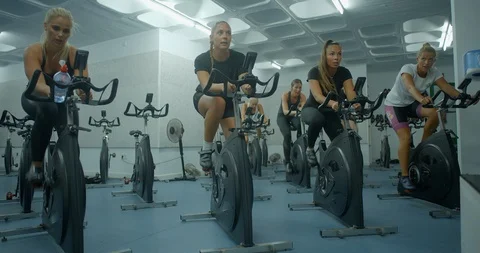 A mixed group of exercise bike riders peddling hard in the gym. Vídeo Stock 85536344