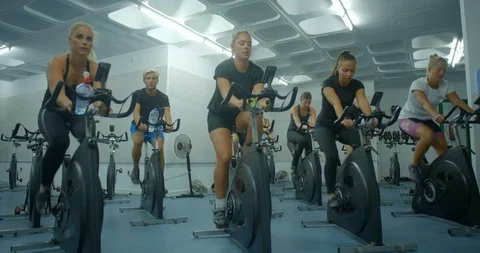 A mixed group of people peddling exercise bikes in a gym. 스톡 동영상 85535522