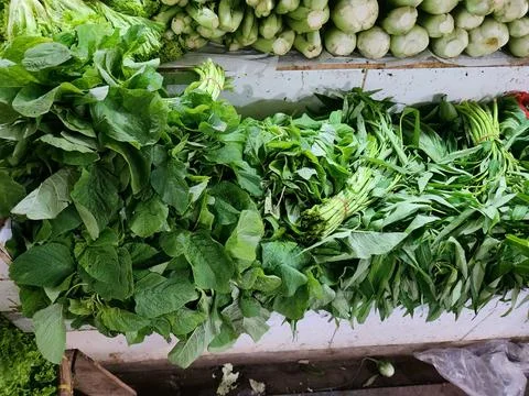 Mixed leafy vegetables on stall table for healthy cooking content. Stock Photos
