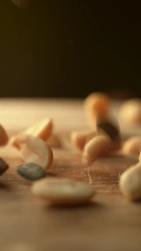 Mixed nuts and seeds falling on a wooden table in slow motion Stock Footage 332923561
