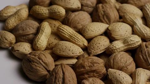 Mixed nuts including walnuts almonds peanuts rotating in pile Stock Footage 328136403