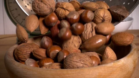 Mixed nuts in shells pouring into bowl in slow motion Video stock 77565262