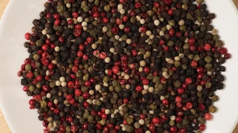 Mixed peppercorns rotating on a white plate Stock Footage 344604573