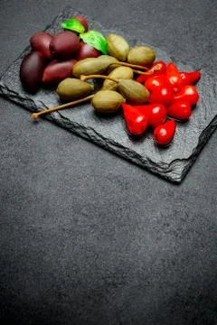 Mixed Pickles on stone serving board. Olives, Capers and peppers Stock Photos