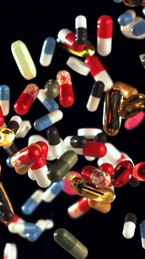 Mixed pills tumbling over black surface with detailed closeup view Filmed on a Stock Footage 335396795