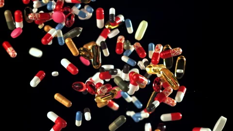 Mixed pills tumbling over black surface with detailed closeup view Filmed on a Stock Footage 335424711