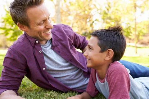 Mixed race Asian boy relaxing in park with his white father Stock Photos