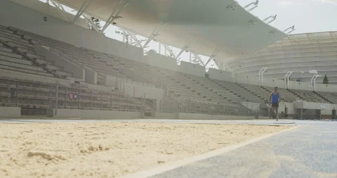 Mixed race athlete doing long jump Stockbeeldmateriaal 124592923