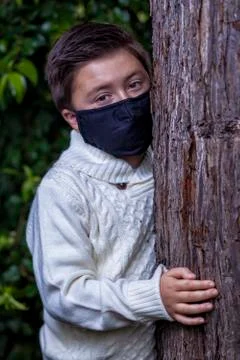Mixed race boy with brown hair wearing a black dusk protective Covid-19 mask Stock Photos