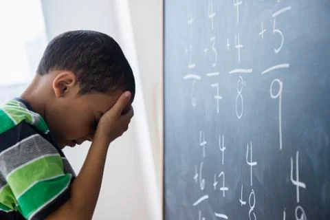 Mixed race boy doing math problems at board in class Stock Photos