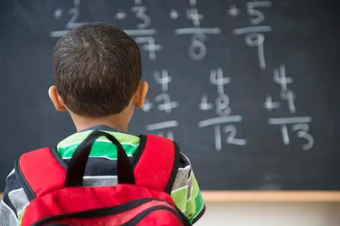Mixed race boy doing math problems at board in class Stock Photos