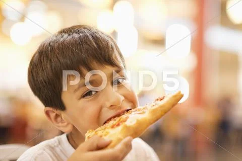 Mixed race boy eating pizza in restaurant Stock Photos