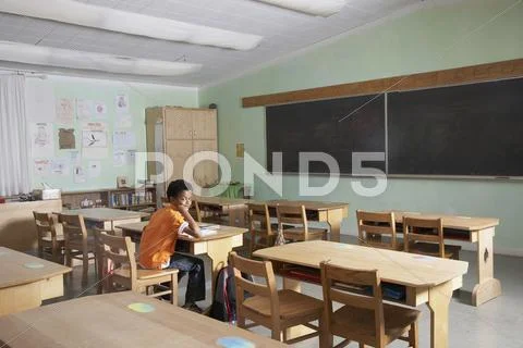 Mixed Race boy in empty classroom Stock Photos
