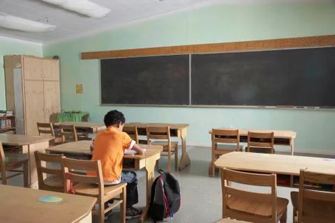 Mixed Race boy in empty classroom Foto stock