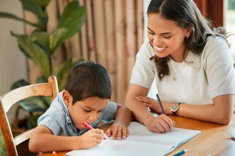 Mixed race boy learning and studying in homeschool with mom. Woman helping son Stock Photos
